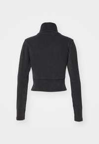 Veste cropped noire avec un col montant, des manches longues, fabriquée en tissu texturé, dotée d'une finition lisse et sans matériel visible.