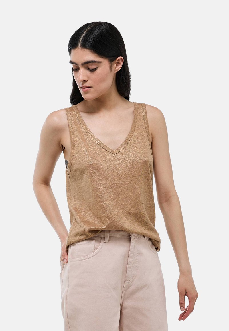 Débardeur tan sans manches avec un décolleté en V et une texture légèrement chatoyante. Associé à un pantalon rose clair, offrant une coupe décontractée.