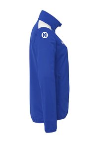 Blå jakke med høj krave, hvide detaljer på skuldrene, lynlåslomme på siden og et logo på overarmen. Fremstillet af et glat stof.