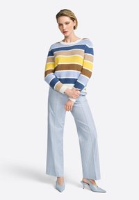 Striped sweater in blue, yellow, and brown with a boat neckline; paired with light blue pinstriped wide-leg trousers and matching heels.