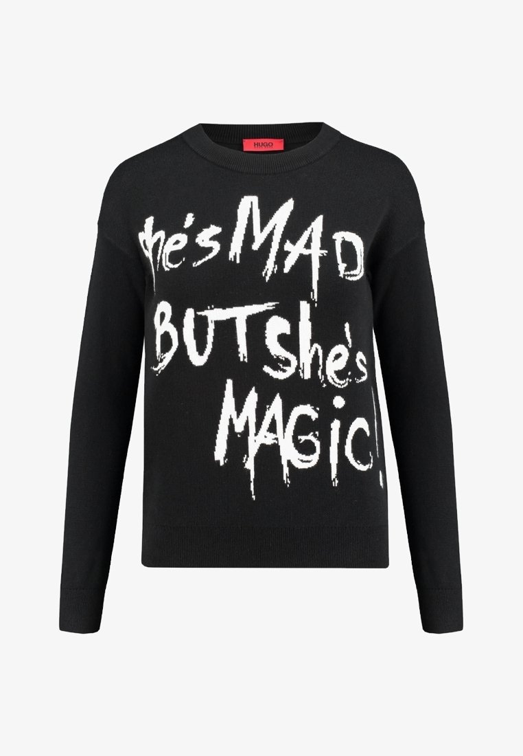 Zwart gebreid sweater met opvallende witte tekst: "Ze is BOOS MAAR ze is MAGISCH!" Ronde halslijn en lange mouwen.