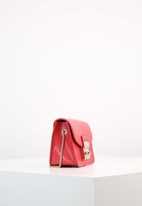 Rote Lederhandtasche mit strukturierten Oberflächen, goldfarbener Hardware, einer Kettenriemen und einem Klappenverschluss. Seitenansicht vor einem weißen Hintergrund.