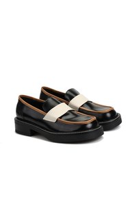 Czarne skórzane mokasyny z grubymi czarnymi podeszwami, brązowym wykończeniem i szerokim beżowym paskiem na górze, pokazane obok siebie na białym tle.