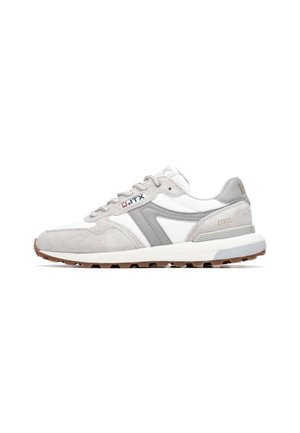 Zapatillas deportivas que combinan cuero blanco y ante gris, con una suela de goma texturizada y una marca sutil en el lateral y el talón.