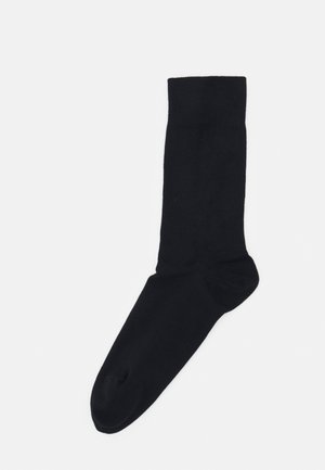 Chaussette noire en tissu lisse, de design hauteur genou avec un embout renforcé et un revers texturé pour une meilleure adhérence.