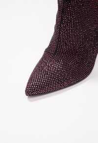 Stivaletto a punta coperto da piccole pietre preziose viola e rosa; texture liscia con design aderente e suola nera.