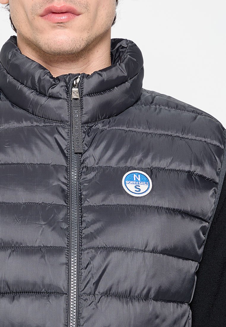 Gilet grigio imbottito con colletto alto, design trapuntato, zip frontale e un distintivo circolare blu con la scritta "NORTH SAILS".