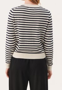 Randig tröja i marinblått och krämfärgat, med ribbad stickad textur, rund halsringning och åtsittande fåll. Utsikt bakifrån, med långa ärmar.