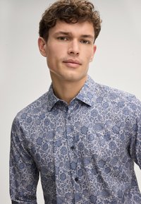Lange mouwen shirt in een blauw en crème bloemenpatroon, met een button-down kraag en borstknopen, gemaakt van lichtgewicht stof.
