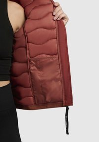 Gequilted, bordeauxkleurige pufferjack met glanzende voering en een zijzak; beschikt over een gestructureerd golfpatroon en een zwarte trekkoord aan de zoom.