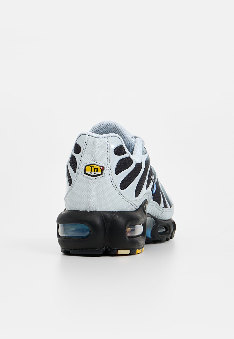 Baskets de sport bleu clair avec accents noirs, empeigne en mesh, design ondulé distinctif et amorti visible dans la semelle.