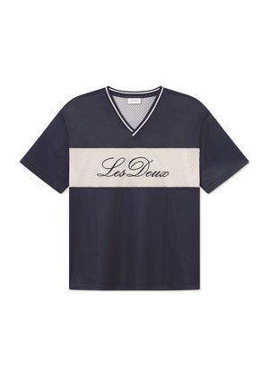 Marineblå mesh-jersey med v-hals, har et kremfarget horisontalt bånd med "Les Deux" i svart skrift over midten. Korte ermer, løs passform.