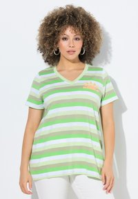 V-kauluksellinen vihreä ja valkoinen raidoitettu t-paita, jossa on lyhyet hihat ja rento leikkaus. Vasemmassa rinnassa on oranssi tassunjälki kirjonta.