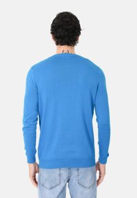 Maglione di cotone blu con maniche lunghe, polsini e orlo a coste, e scollatura rotonda. Tessuto notablemente morbido e distribuzione del colore uniforme.