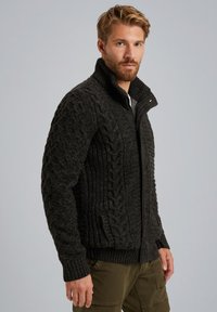 Mørkegrå strikket zip-up sweater med høj krave, der har teksturerede kabelmønstre på ærmerne og kroppen, samt ribbede manchetter og kant.