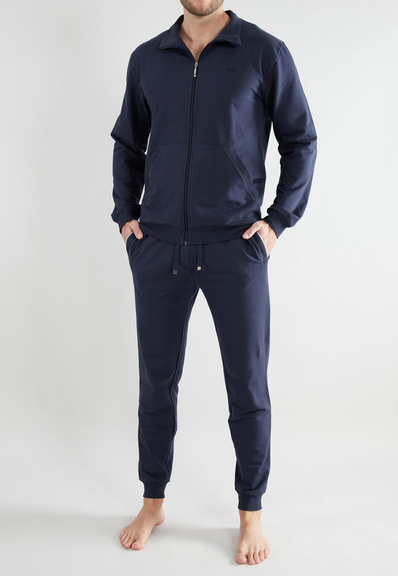 Navy blue tracksuit made of soft cotton, featuring a zip-up jacket with a collar and pants with an elastic waistband and cuffed ankles.