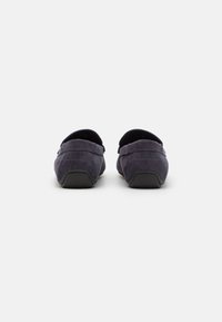 Chaussures slip-on en daim bleu marine avec un bout arrondi et une finition texturée, dotées d'une semelle en caoutchouc noire et de détails de couture.