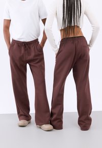 Bruine relaxfit sweatpants met een elastische tailleband en trekkoord, voorzien van een achterzak en een gladde katoenen textuur.