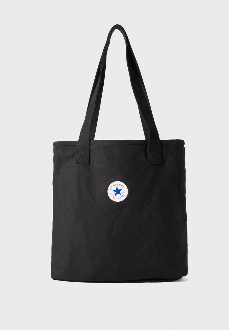 Saco de lona preto com duas alças resistentes. Apresenta um emblema redondo nas cores vermelha, branca e azul, com o texto "Converse All Star".