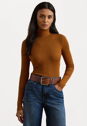 Rostorange ribbade turtleneck-tröja, figursydd design. Matchad med högmidjade denimbyxor och ett brunt bälte med ett metallspänne.