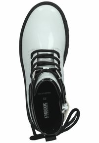 Botín de piel sintética blanca con cordones negros, puntera redonda y suela texturizada negra. Cuenta con un detalle de cremallera y un interior acolchado.