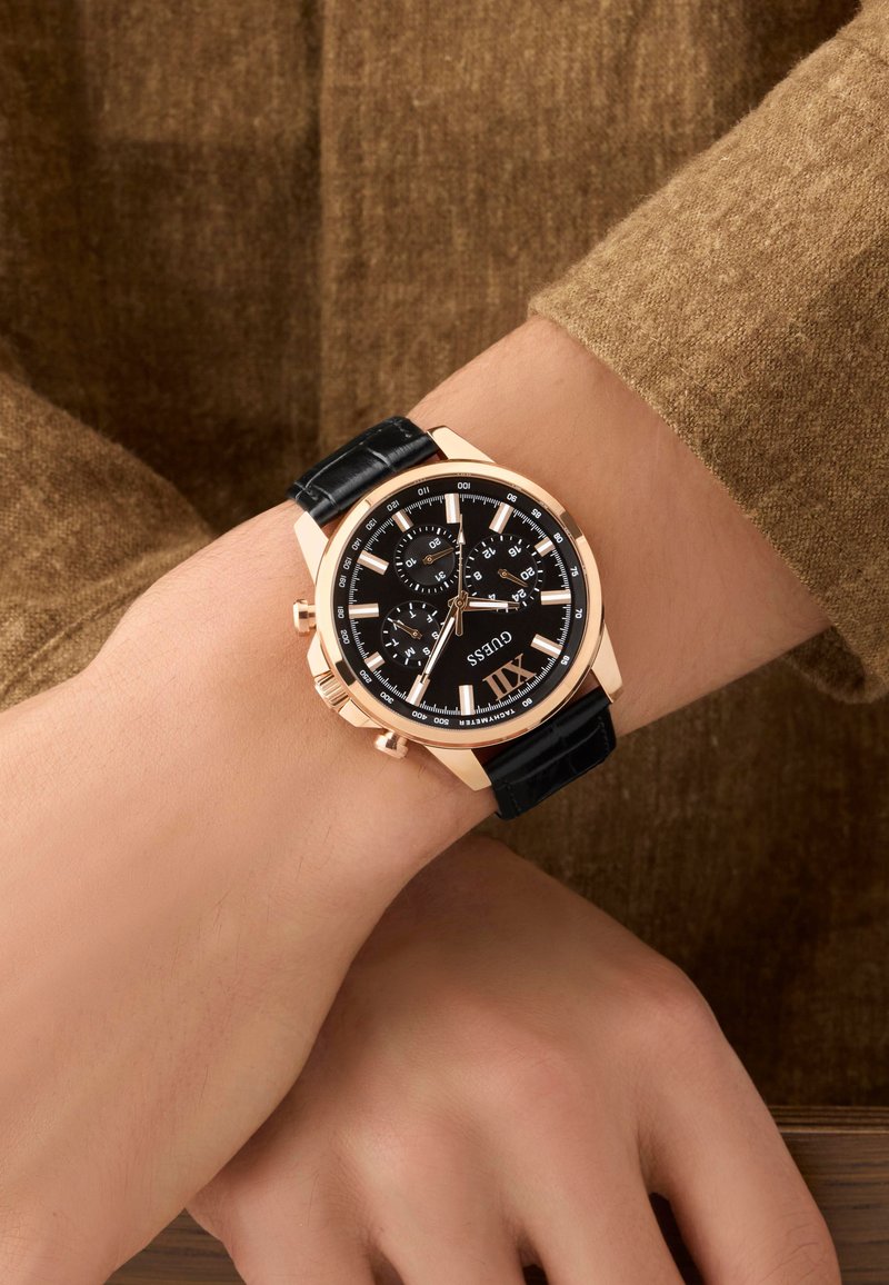 Montre chronographe noire avec un boîtier en acier inoxydable doré rose, un bracelet en cuir noir, des index d'heure blancs et un cadran texturé.