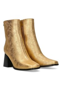 Botas de tobillo metálicas doradas con punta afilada, que cuentan con un cierre de cremallera lateral y un tacón negro grueso, con textura suave y un diseño elegante.