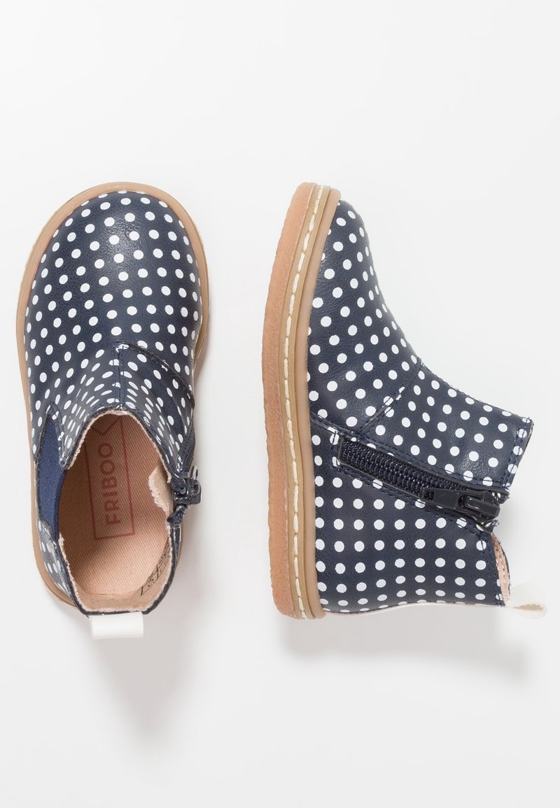 Bottes pour tout-petits bleu marine avec des pois blancs, semelles beige, fermetures éclair latérales et panneaux élastiques pour un enfilage facile sur fond blanc.