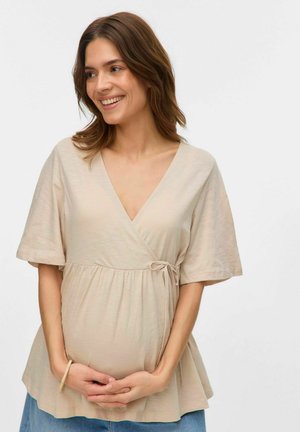 Top beige de estilo envolvente con mangas cortas, ajustado debajo del busto, textura suave y un detalle de lazo en la cintura, apto para ropa de maternidad.