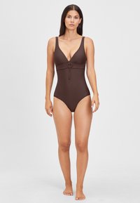 Brauner Einteiler-Badeanzug mit tiefem V-Ausschnitt und einem dekorativen Ring in der Mitte. Der Stoff wirkt glatt und leicht dehnbar.