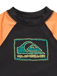 Rash guard de manga corta en negro y naranja con un logo de Quiksilver en teal y amarillo con diseño de ola y costuras en contraste.