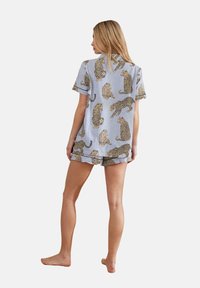 Leopard-print sleepwear set featuring a short-sleeve top and shorts in light blue. Fabric is soft, with a relaxed fit and cuffed sleeves.