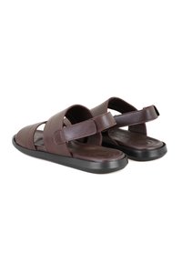 Braune Leder-Sandalen mit einem multiple Riemen-Design und verstellbarem Klettverschluss. Flache schwarze Gummisohle mit leichter Krümmung.