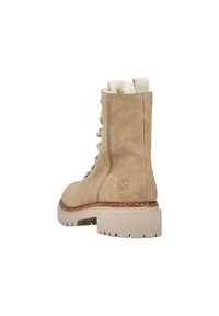 Botín de ante beige hasta el tobillo con una suela blanca gruesa, que cuenta con ojales metálicos decorativos, costuras en contraste y una lengüeta trasera.