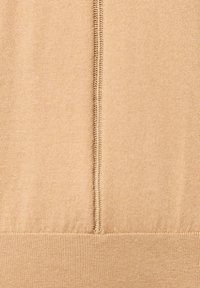 Beżowa dzianina z delikatnym połyskiem. Posiada środkowy szew z widocznym szwem oraz prążkowany dół.