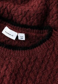 Mörkröd stickad tröja med ett texturerat mönster och svart ribbad halsringning. Etiketterna anger varumärket "name it" och storlek 7-8 år, 128.