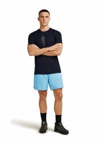 Navy t-shirt with tree graphic, light blue shorts, black socks, and black athletic shoes. Plain design, lightweight fabric, casual fit.