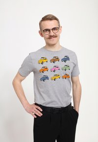 Grijze t-shirt met korte mouwen met een kleurrijke print van cartoonauto's in verschillende kleuren: geel, roze, blauw, oranje en groen.