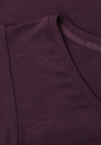 Gros plan sur un pull en maille violet foncé plié, montrant une texture côtelée détaillée et un col en V.