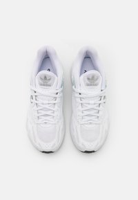 Fehér Adidas sneakers, hálós és bőr anyagból, kerek orral, fehér fűzőkkel és ezüst logóval a nyelvén.