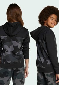 Svart och grå camouflage-huvtröja med långa ärmar, ribbad mudd och en kontrasterande solid svart övre del.