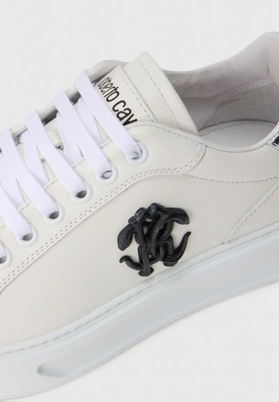 Adidași din piele albă cu accent logo negru, talpă din cauciuc și șireturi albe. Textură netedă cu detalii cusute pe laturi.