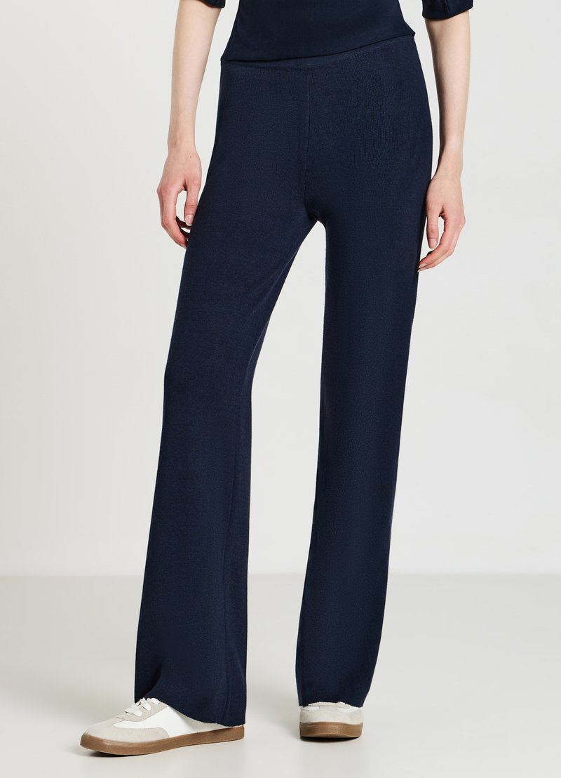 Marineblaue, weit geschnittene Hosen aus strukturiertem Stoff, mit hohem Bund und kombiniert mit hellen Sneakers.