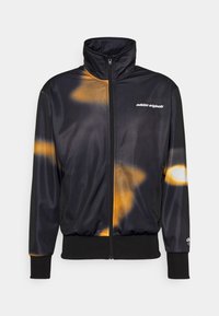 Čierne a oranžové trblietavé zapínacie sako s vysokým golierom, pružnými manžetami a pásom. Na prednej strane sa nachádza logo "adidas originals".
