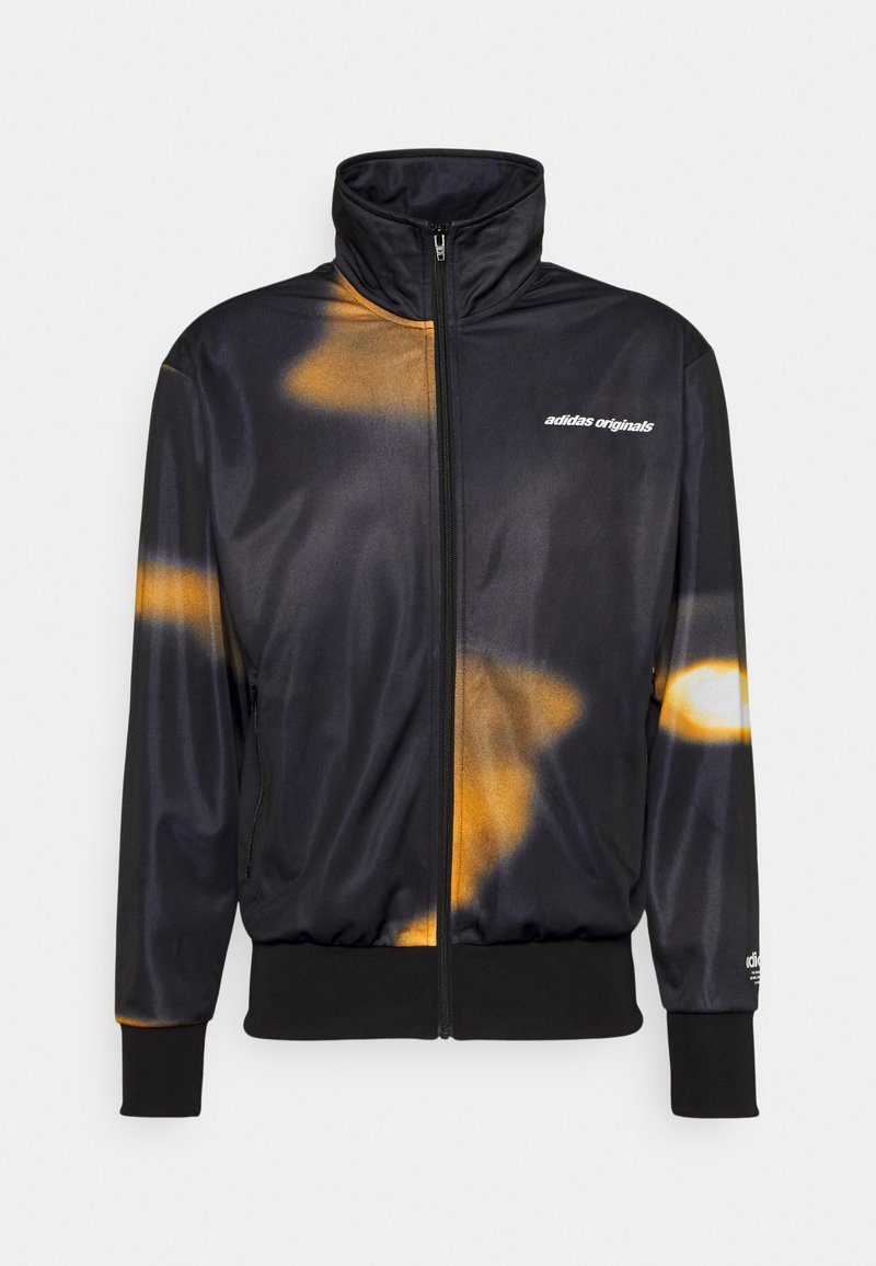 Črno in oranžno vezno zadrgo jakna z visokim ovratnikom, elastičnimi manšetami in pasom. Na sprednjem delu ima logo "adidas originals".