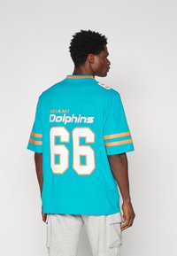 Φανέλα Miami Dolphins σε φωτεινό τυρκουάζ με πορτοκαλί λεπτομέρειες. Διαθέτει μεγάλο λευκό αριθμό "66" στην πλάτη και κείμενο "MIAMI Dolphins" από πάνω.