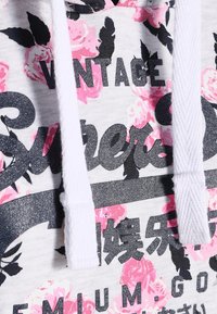 Felpa con cappuccio in tessuto grigio, motivo floreale rosa e lettering nero. Presenta stringhe bianche e un finish testurizzato.