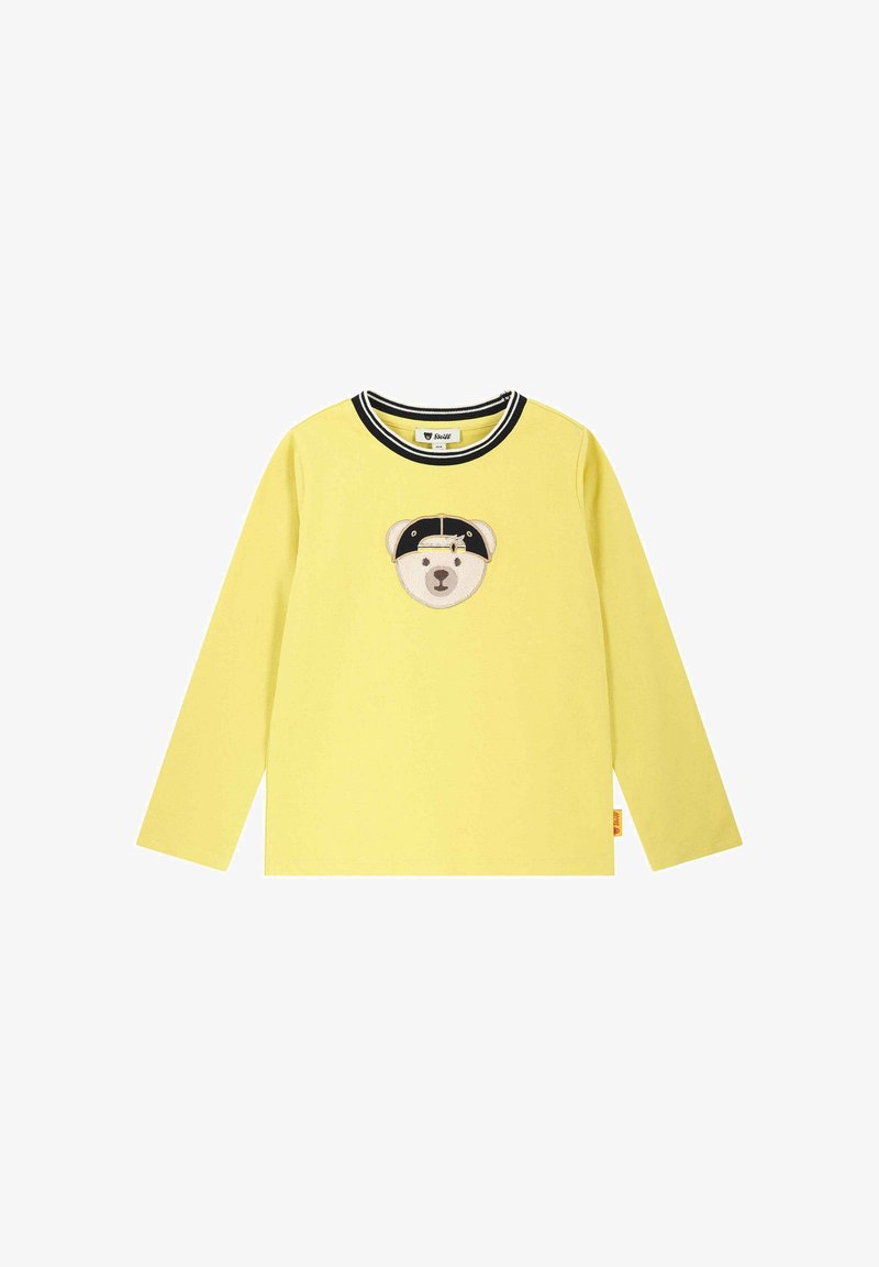 Camisa de manga larga amarilla de algodón suave con un diseño de cara de oso que lleva un sombrero negro y un cuello de rayas en blanco y negro.