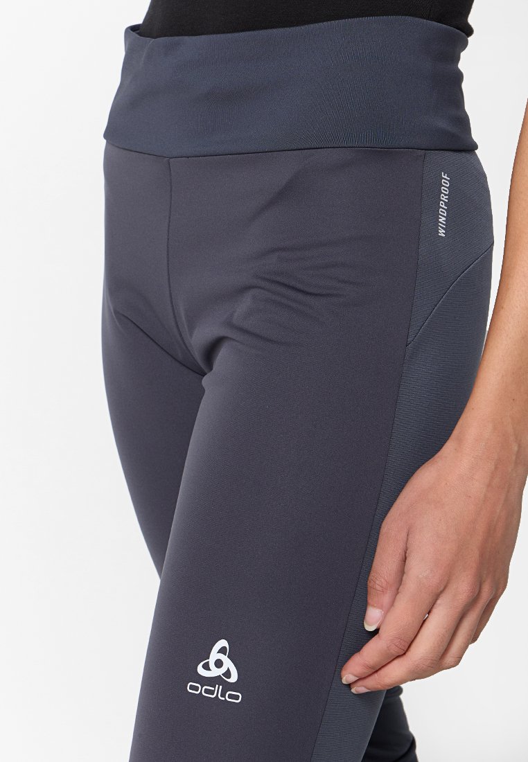 Hochtaillierte, winddichte Leggings in Dunkelgrau, mit glatter Textur, Odlo-Logo und einem figurbetonten Design mit seitlichen Akzenten.