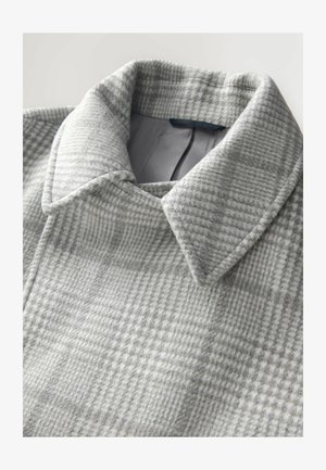 Hall grisikirves villakangas kerge tekstuuriga; omab klassikalist kaelust ja struktureeritud kaeluse disaini; peened mustrimuutused.